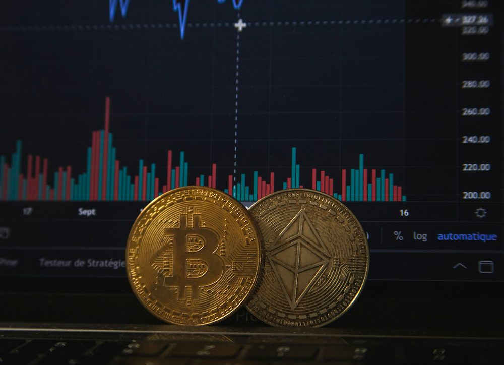 Bitcoin and Ethereum coins on a laptop keyboard in front of a chart